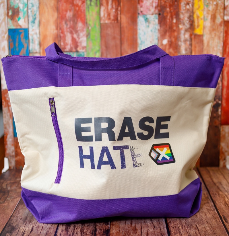 Product Description: Show your pride with the Contemporary Erase Hate Zippered Tote Bag, and spread our mission at the beach, while running errands, or on the way to work or school. The bag is made of durable polyester and measures 16" H x 19" W x 5 1/2" D. Features a top-zip closure and a zippered front pocket. Shipping included.</br> Contemporary Erase Hate Zippered Tote Bag